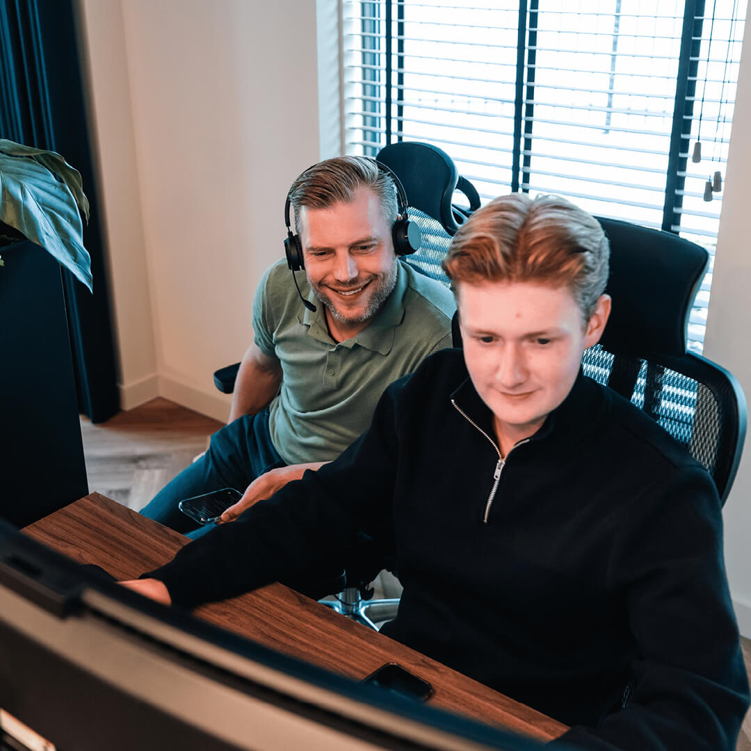 Twee medewerkers achter computer, waarvan één met headset, werken aan grip op juiste vervangingsmomenten